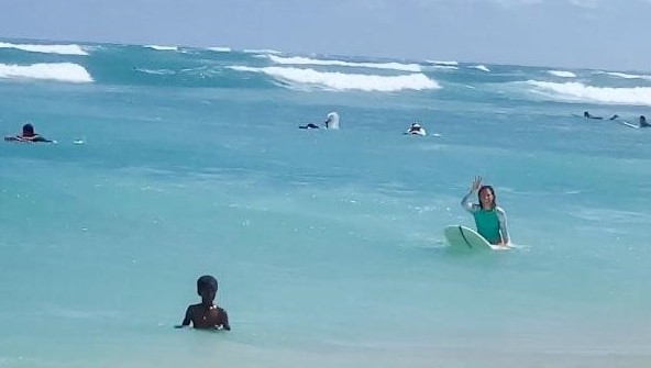 Girl sitting on a surfboard in clear blue water