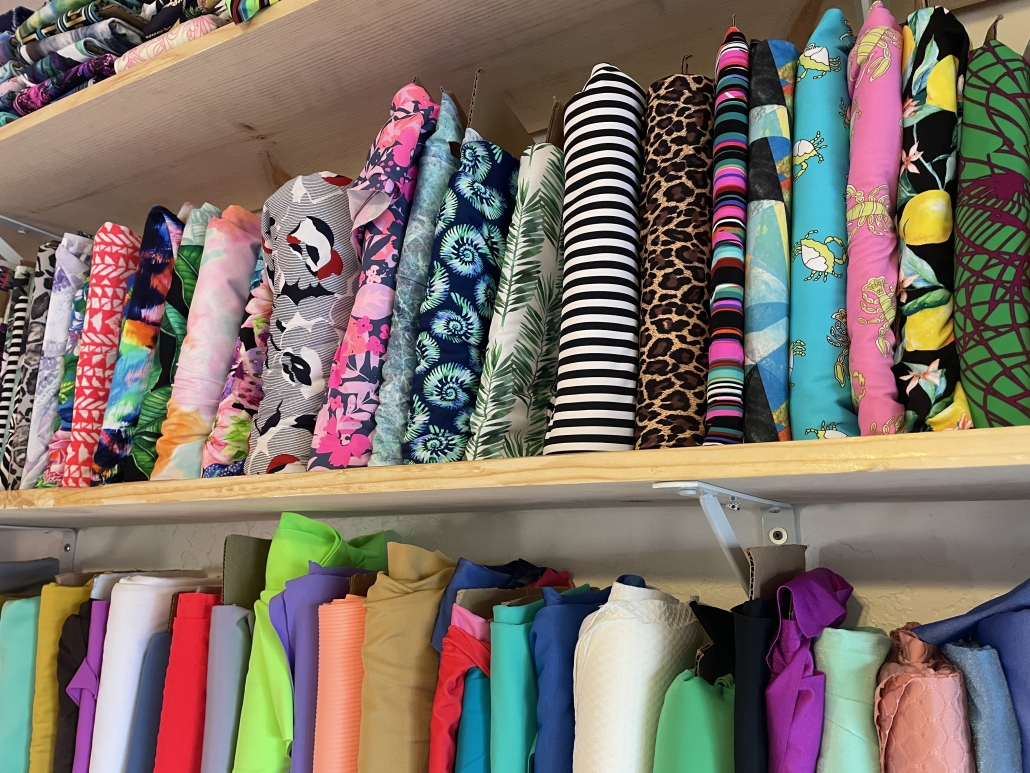 different color fabrics for bikinis line the shelves in a bikini shop