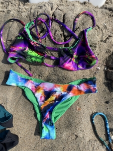 purple and green bikini sites on the sand at the beach