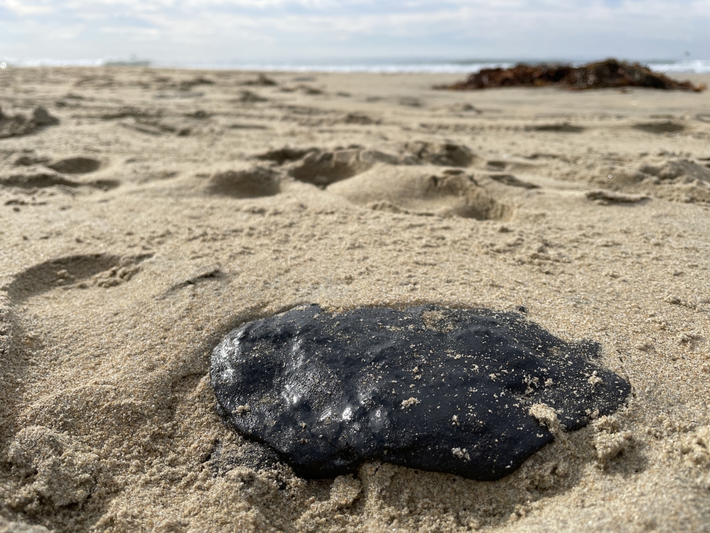 black oil tar sits on the sand in Newport Beach, CA